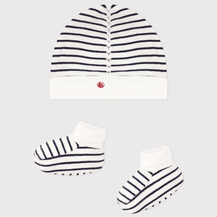 Scopri il dolce set di cappellino e scarpine firmato Petit Bateau, pensato per accompagnare il tu...