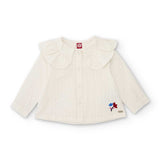 Camicia bianca per bambina con colletto arricciato e piccoli dettagli colorati vicino all'orlo